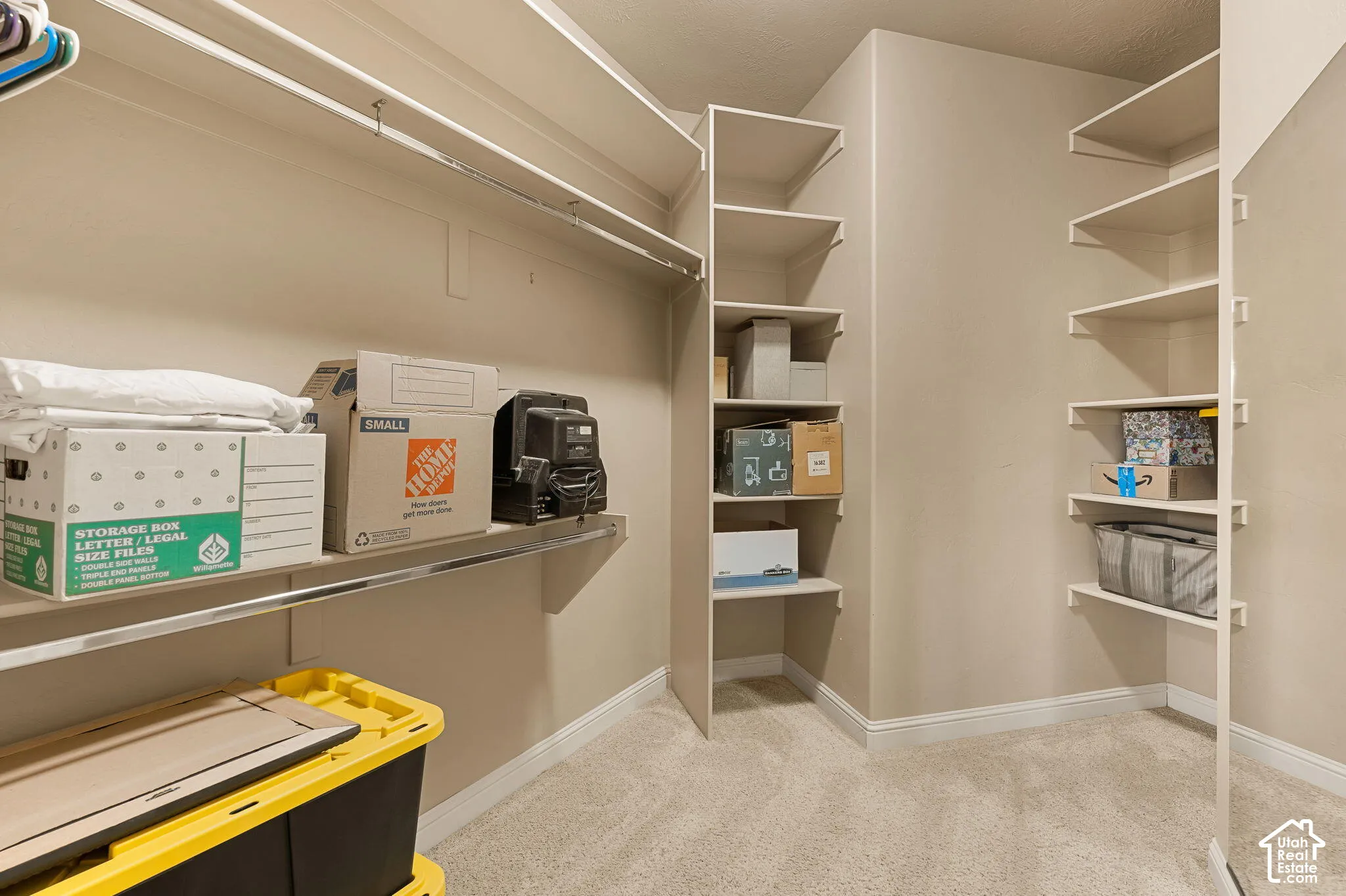 Carpeted walk-in closet featuring extensive built-in shelving, multiple hanging rods, and neutral wall tones