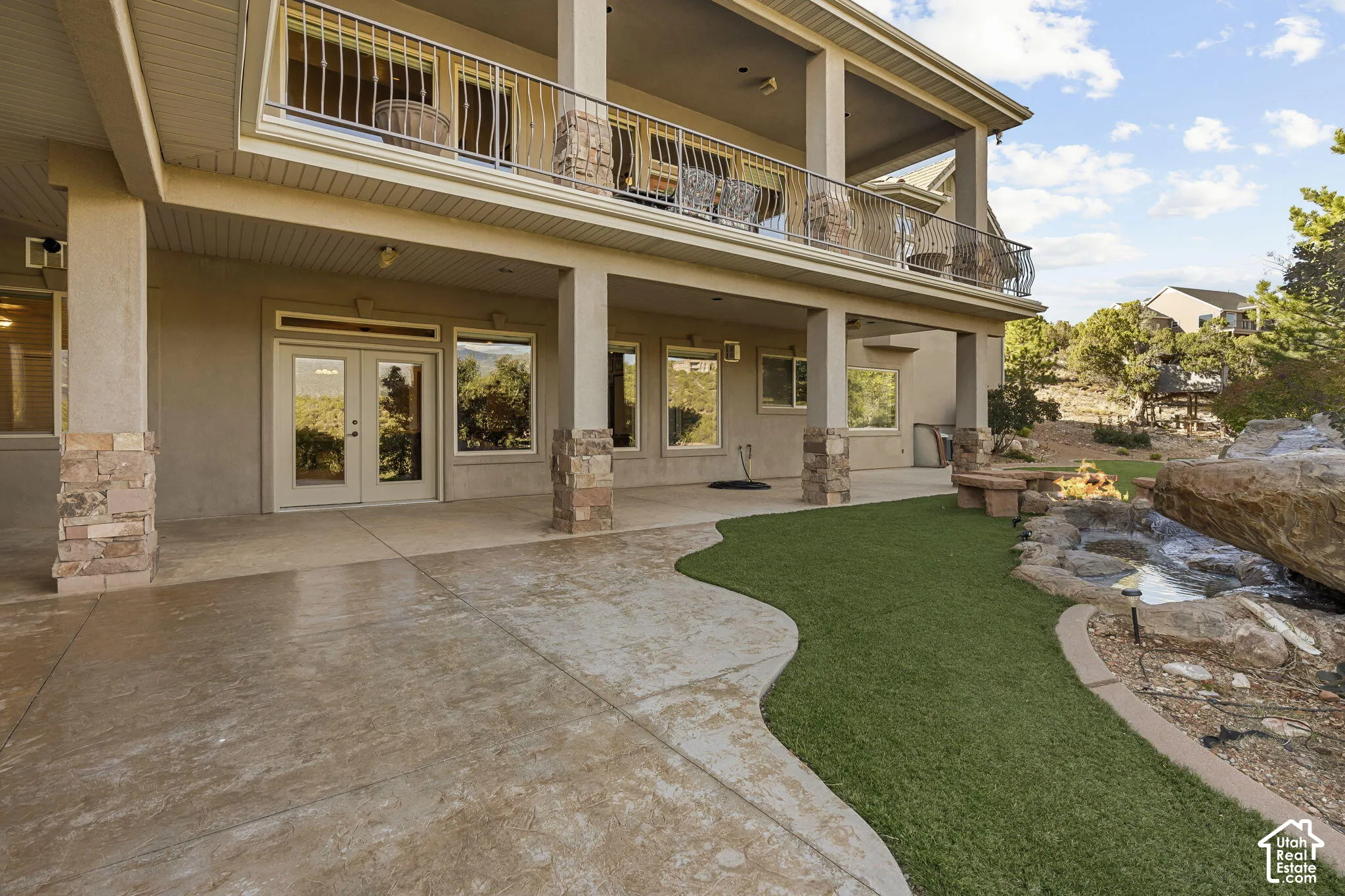 Expansive lower patio with stamped concrete, stone-clad columns, and direct outdoor access