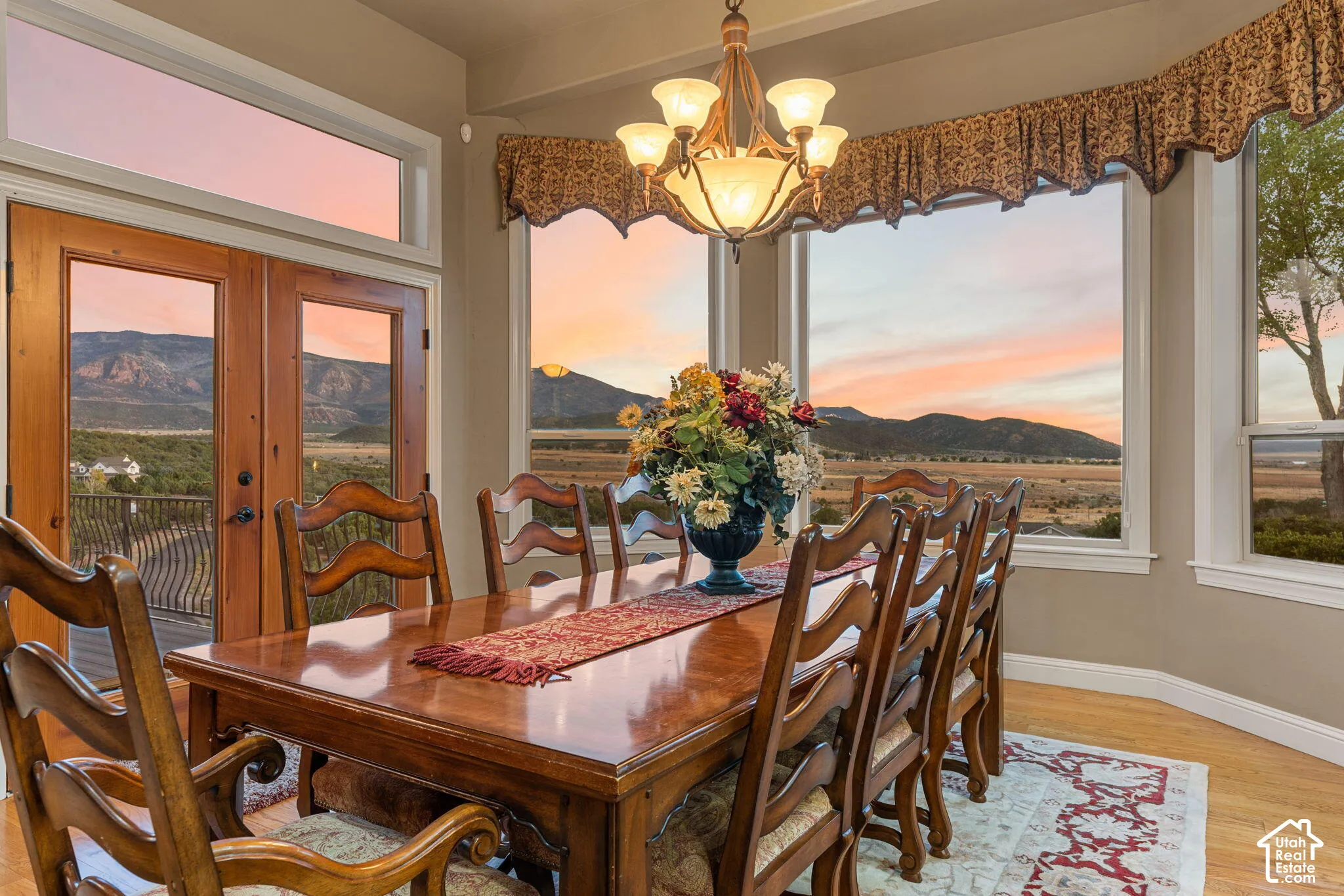 Expansive dining area with hardwood flooring, large picture windows, and a multi-light chandelier