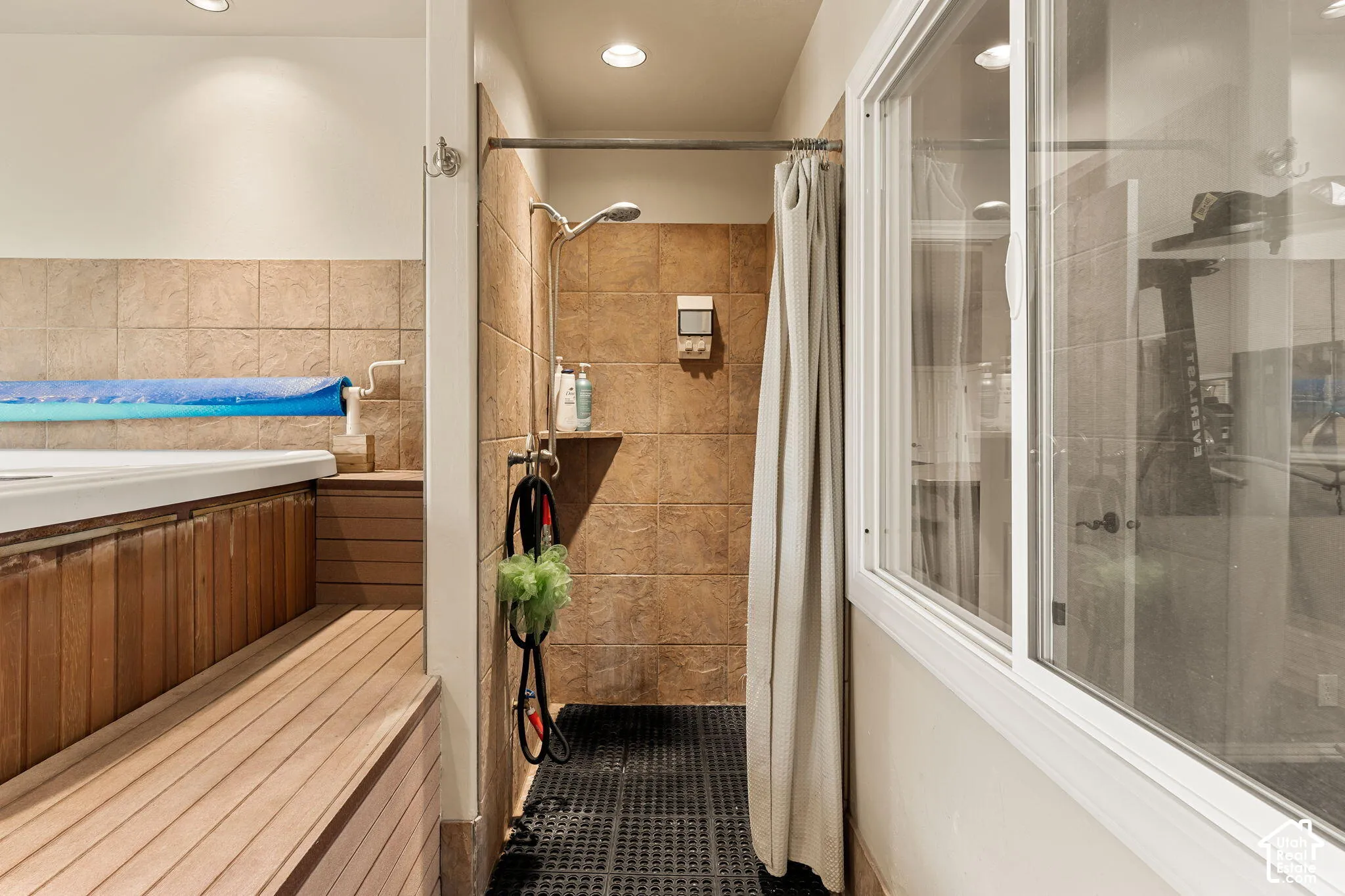 Shower area with floor-to-ceiling tile, an adjacent built-in spa with wood paneling, and a wood-slat surround