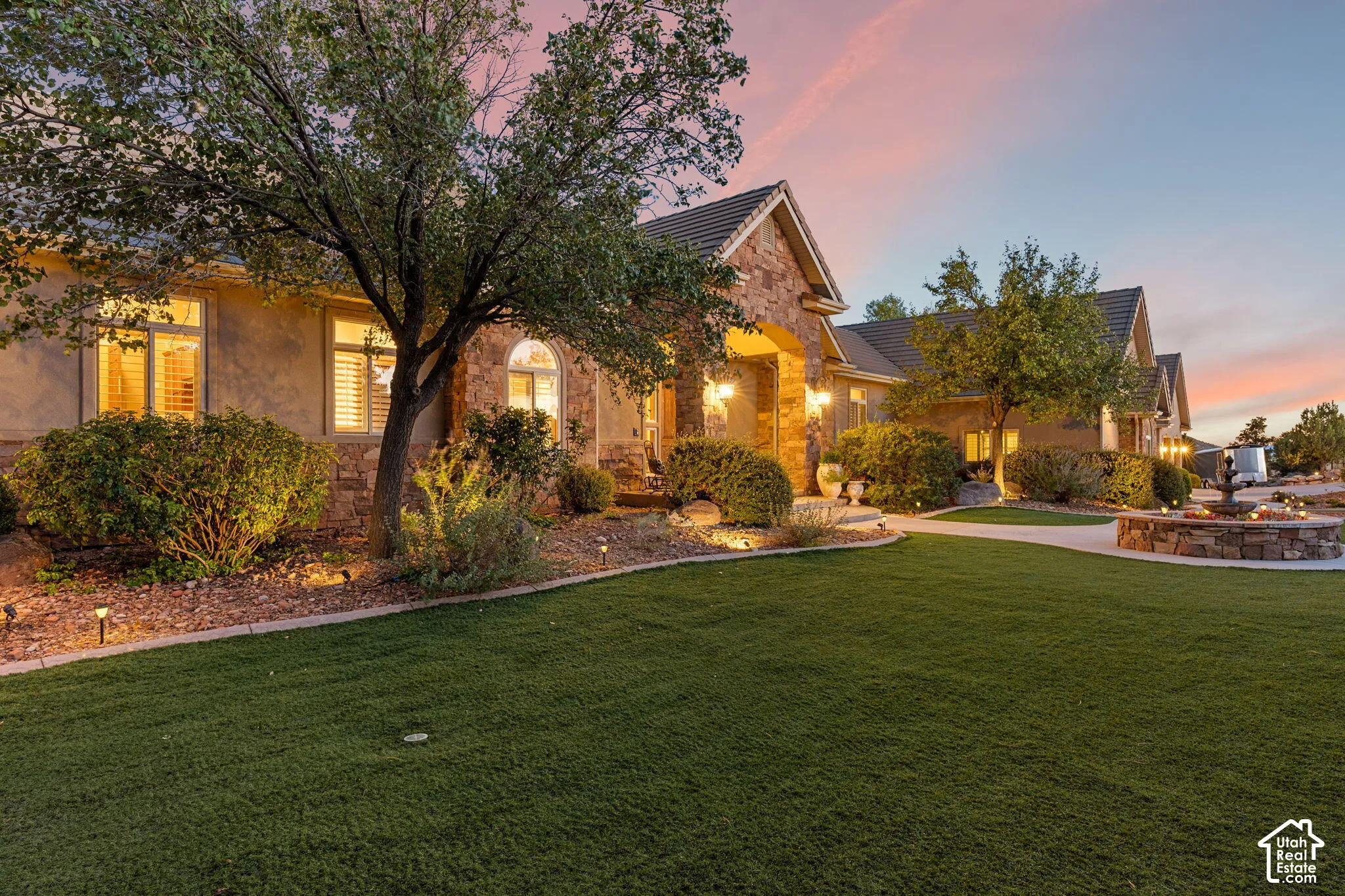 Stone-clad exterior with arched entryways, extensive landscaping, and a manicured lawn