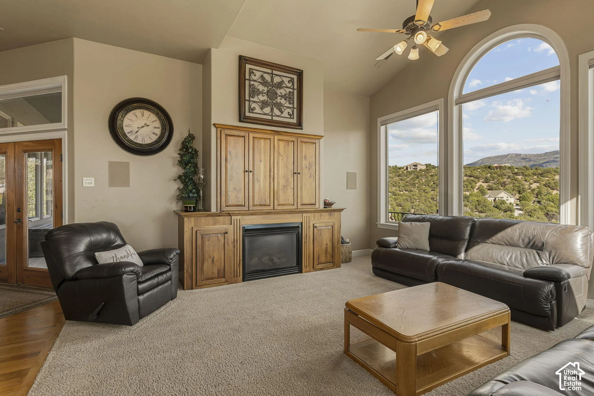 Vaulted ceiling, arched picture window, integrated cabinetry, built-in fireplace, and wood-finish French doors
