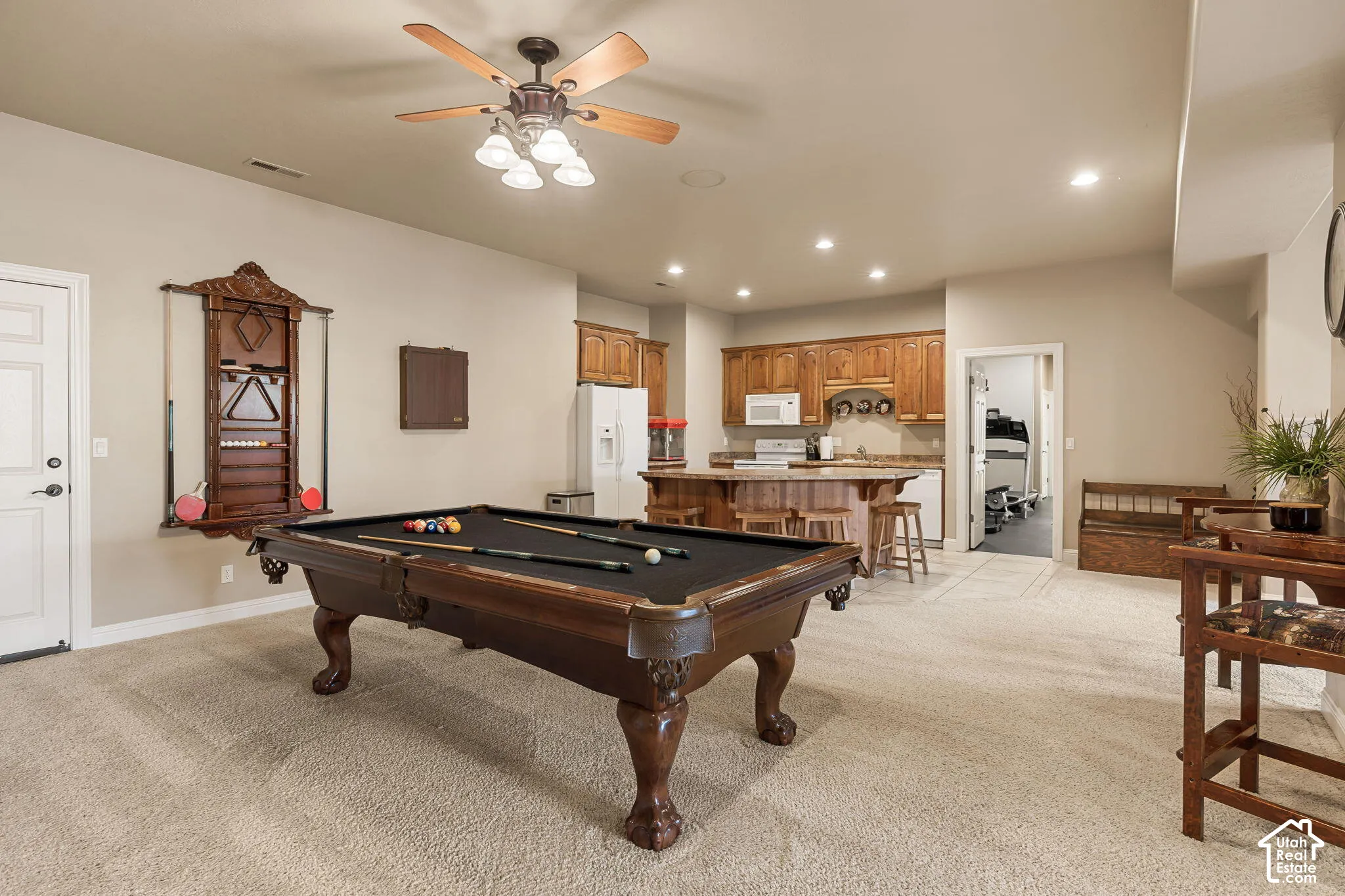 Recessed lighting, ceiling fan, warm wood cabinetry, and a built-in bar with seating
