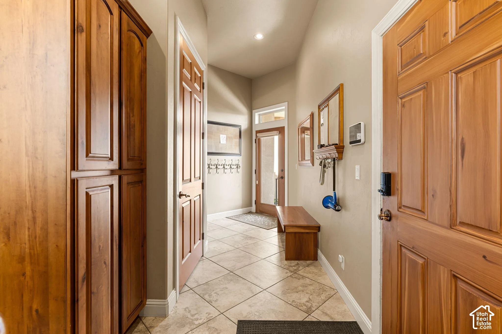 Hallway featuring a built-in wood-finish cabinet, wood-finish doors, and tiled flooring