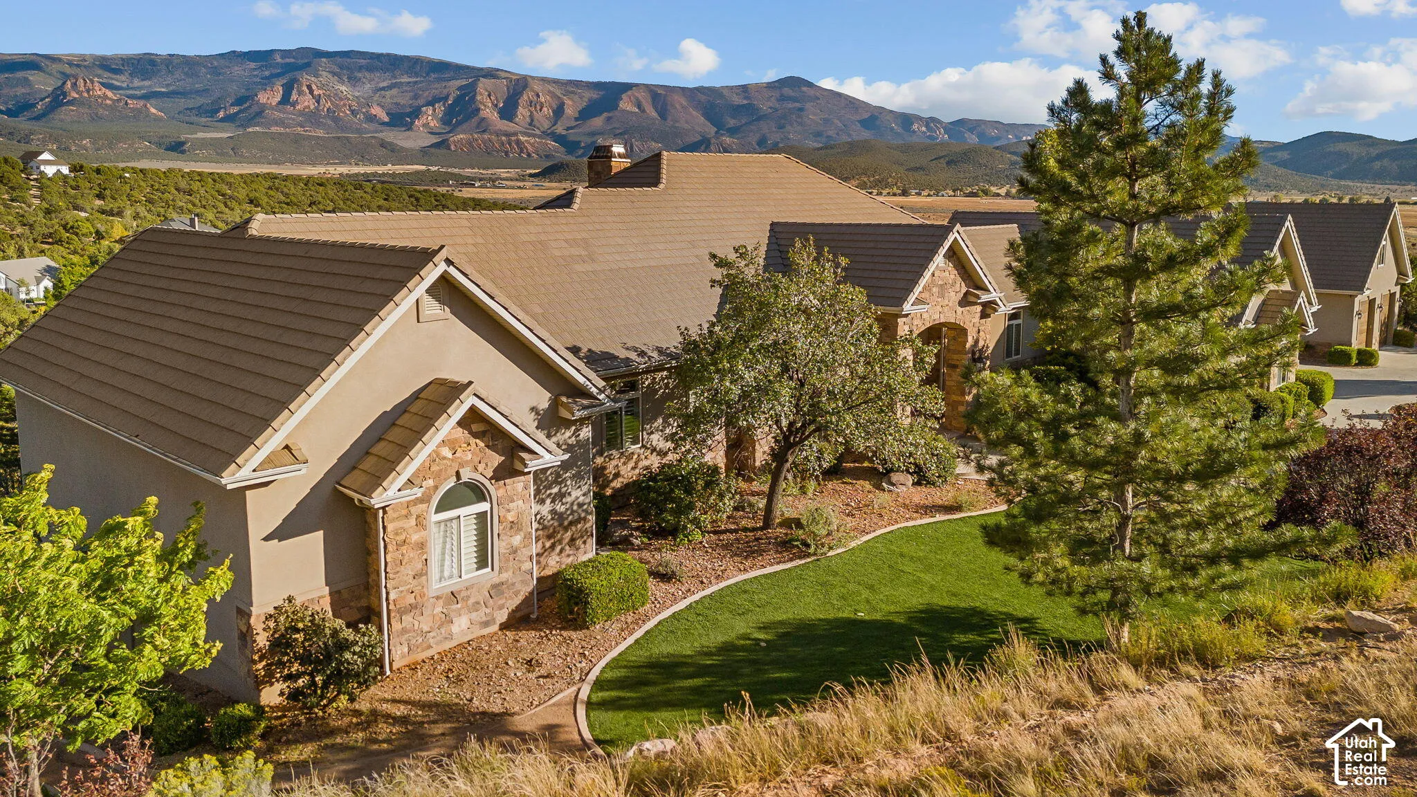 Stucco and stone exterior with arched window details, a tiled roof, and a manicured lawn