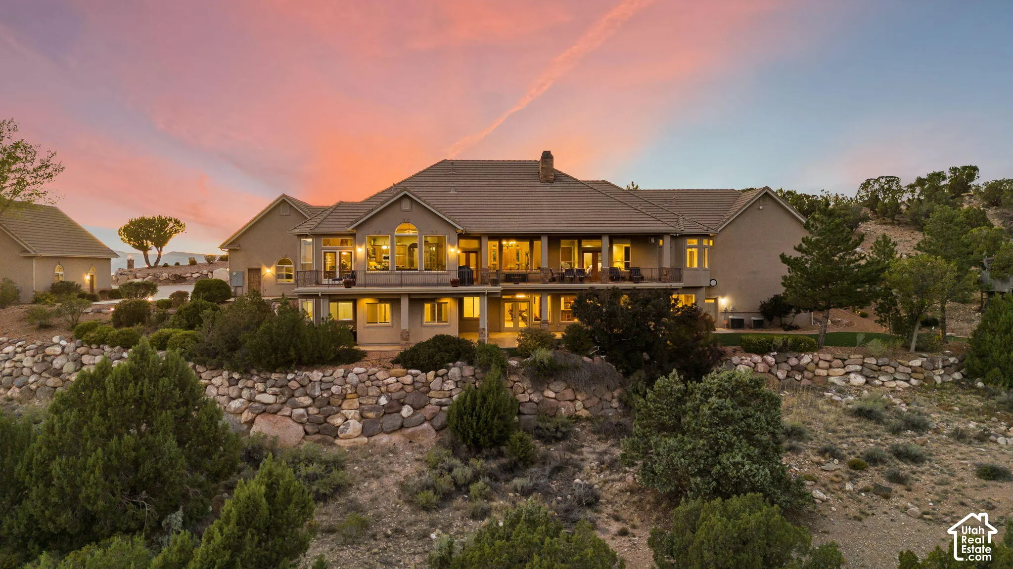 Expansive property featuring multi-level construction, multiple balconies, a stone-faced retaining wall, and mature landscaping