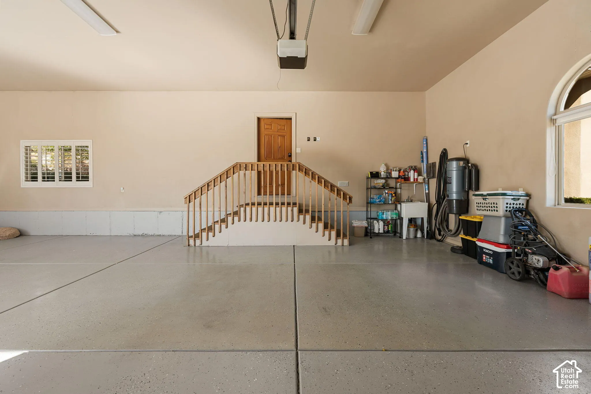 Spacious garage featuring a durable epoxy floor, interior access door, and integrated utility sink