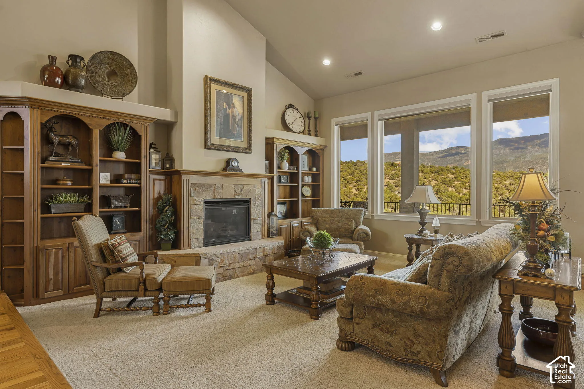 Vaulted ceilings, built-in shelving, stone fireplace with hearth, recessed lighting, and wall-to-wall carpeting