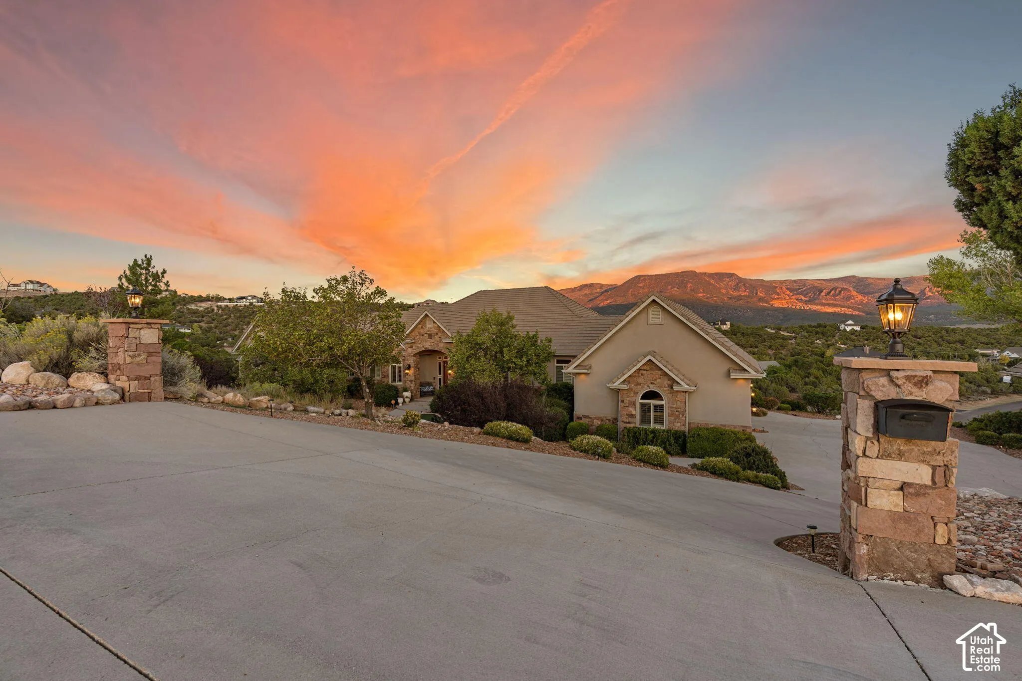 Paved driveway leading to a stucco and stone exterior residence