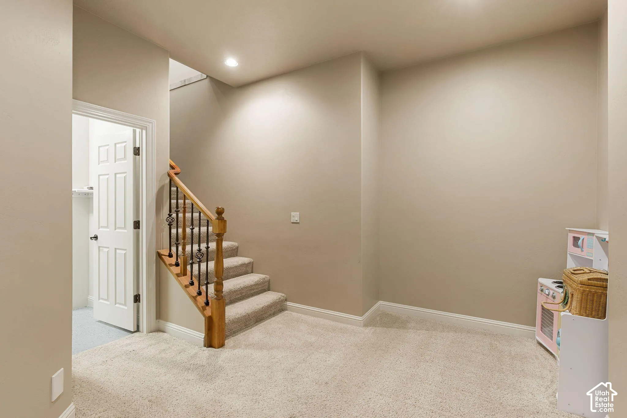 Carpeted stairs with wood handrail and wrought iron balusters