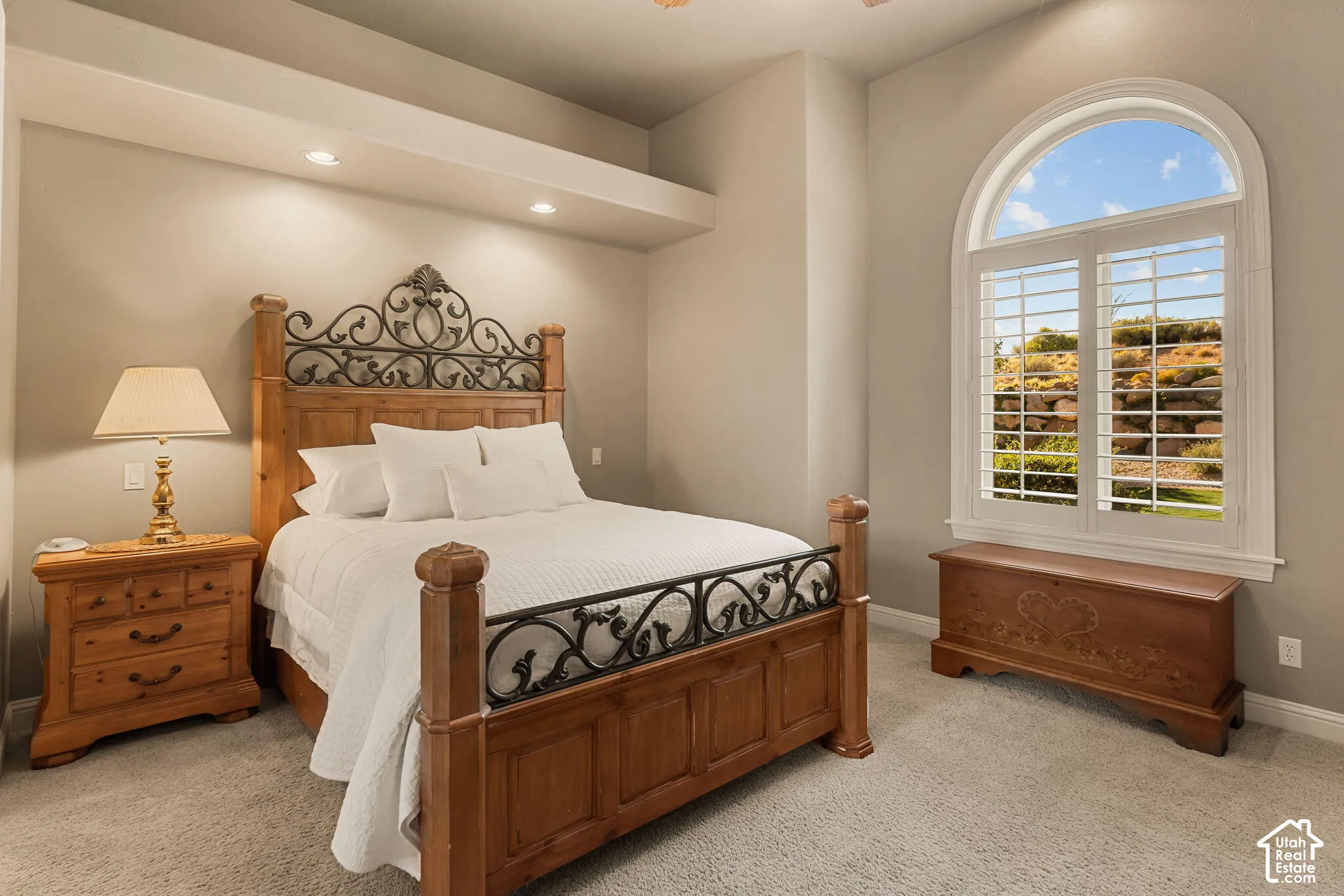 Arched window with plantation shutters, recessed lighting, carpet flooring, and a wall alcove