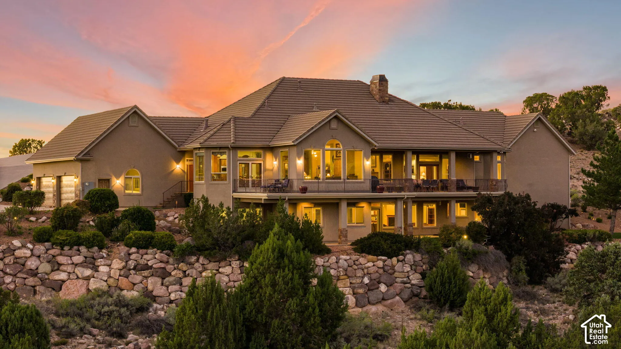 Multi-level residence featuring a stucco exterior, tiled roof, multiple arched windows, and an integrated two-car garage