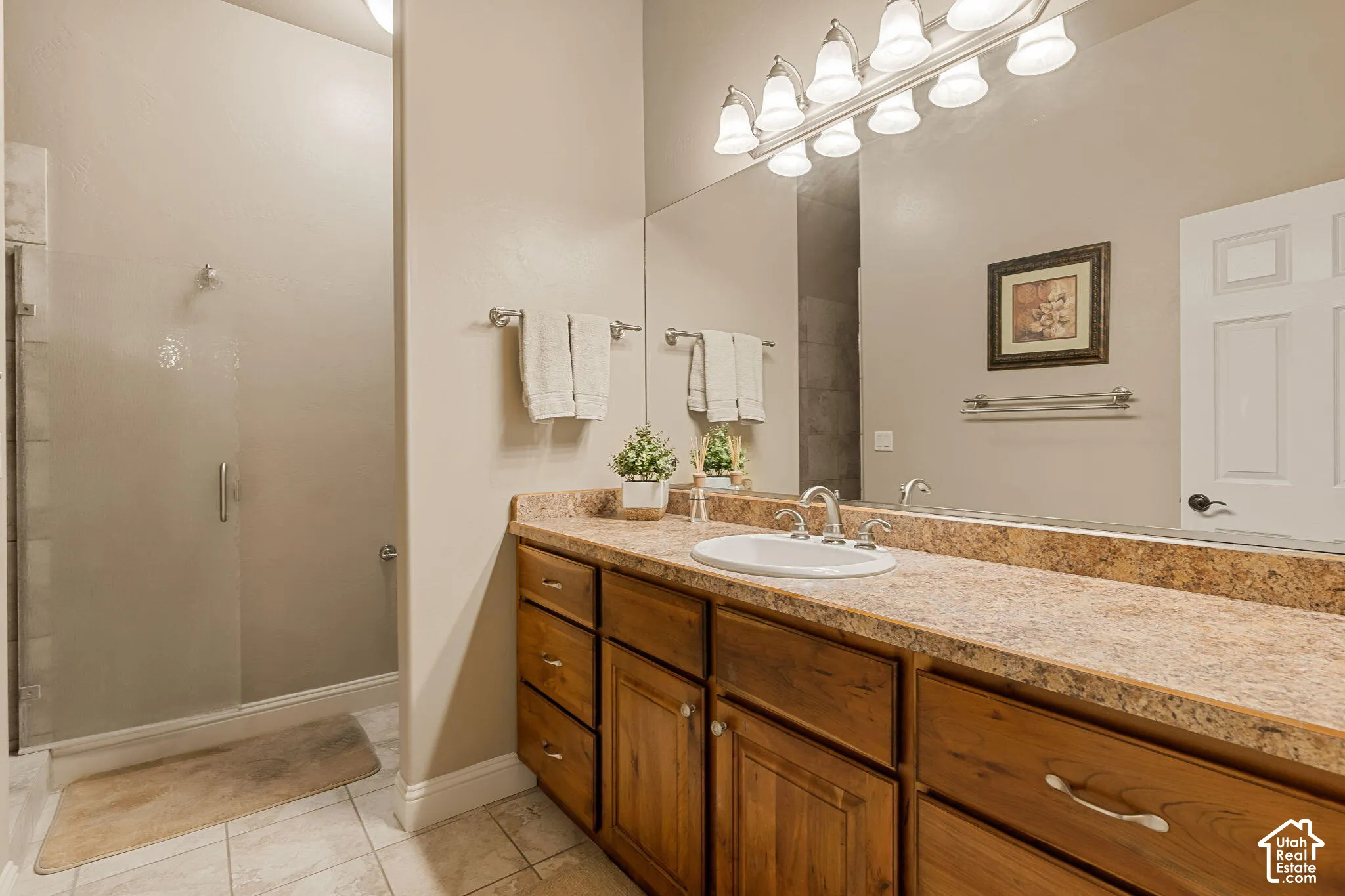Glass-enclosed shower, wood-finish vanity with ample storage, integrated sink, and a spacious countertop