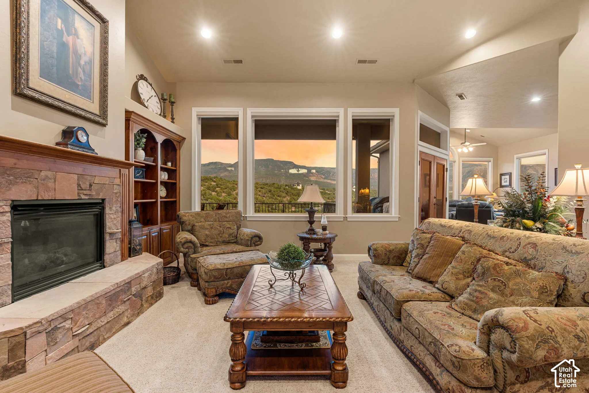 Stone-faced fireplace with hearth, built-in wood cabinetry, recessed lighting, and multiple windows