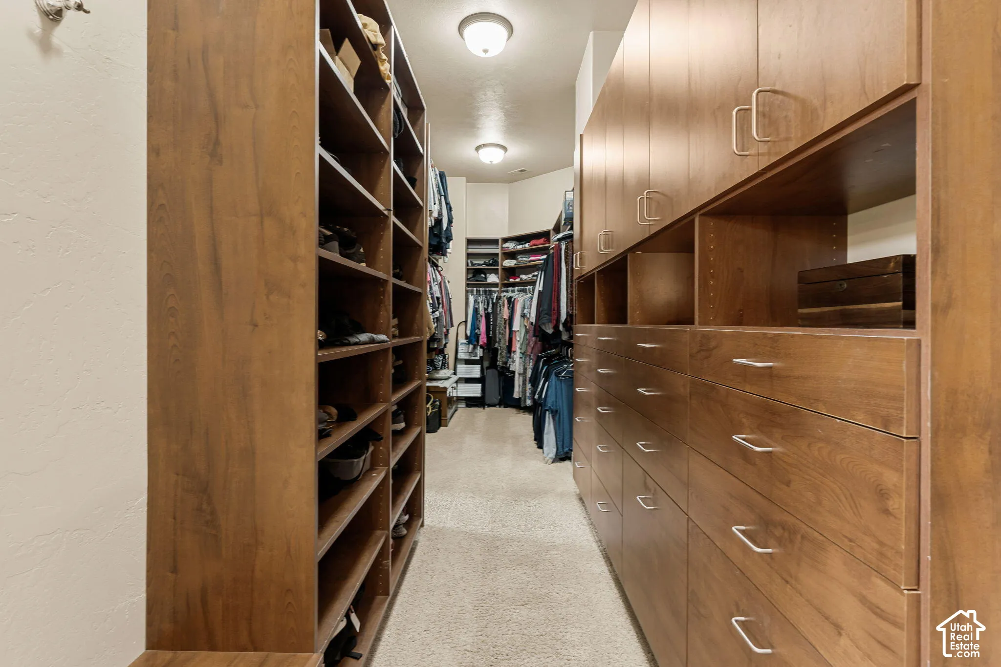 Expansive custom closet featuring extensive wood-finish shelving, built-in drawer storage, and integrated overhead cabinetry