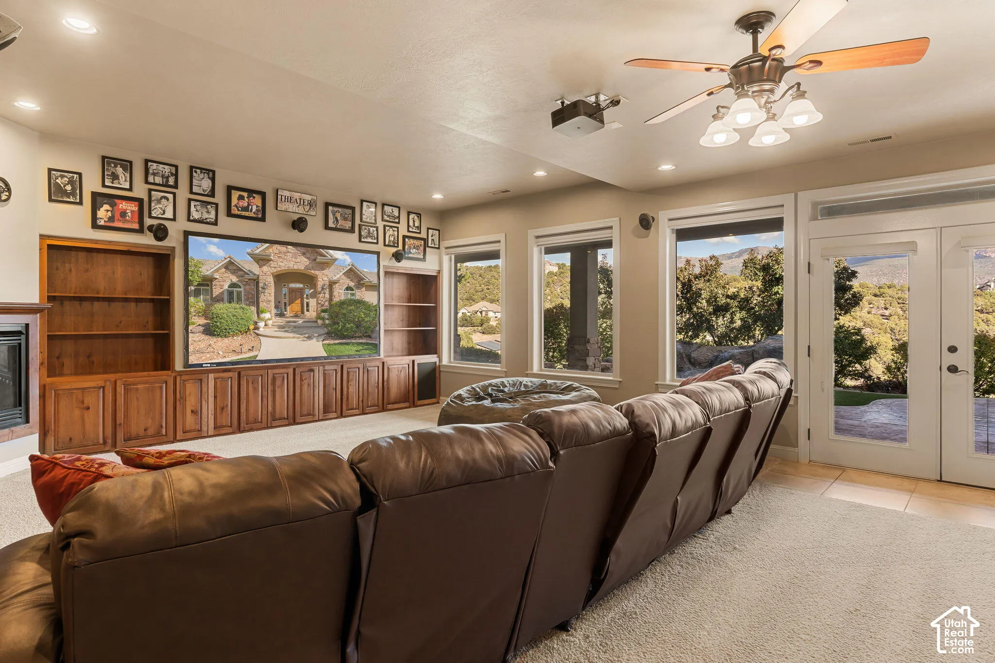 Built-in entertainment center with wood cabinetry and shelving, recessed lighting, ceiling fan, multiple windows, and exterior access via double glass doors