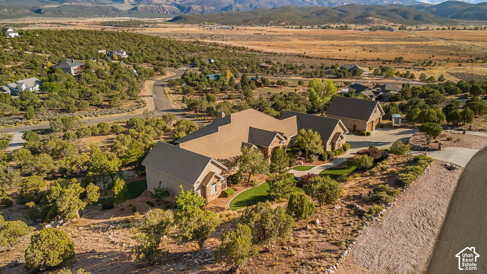 Expansive property featuring a multi-gable roofline, stone and stucco exterior, paved driveway, and mature landscaping