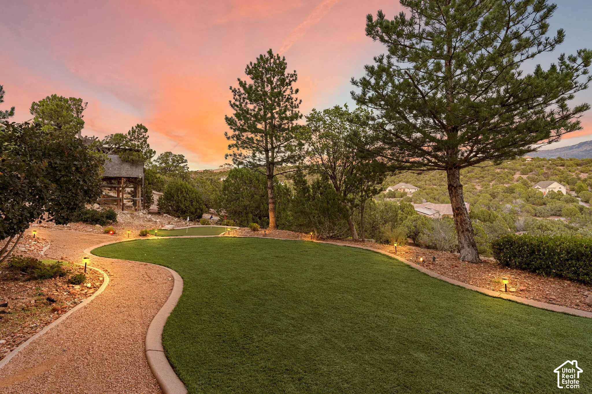 Curved gravel pathway with integrated ground lighting, artificial turf lawn, and mature trees