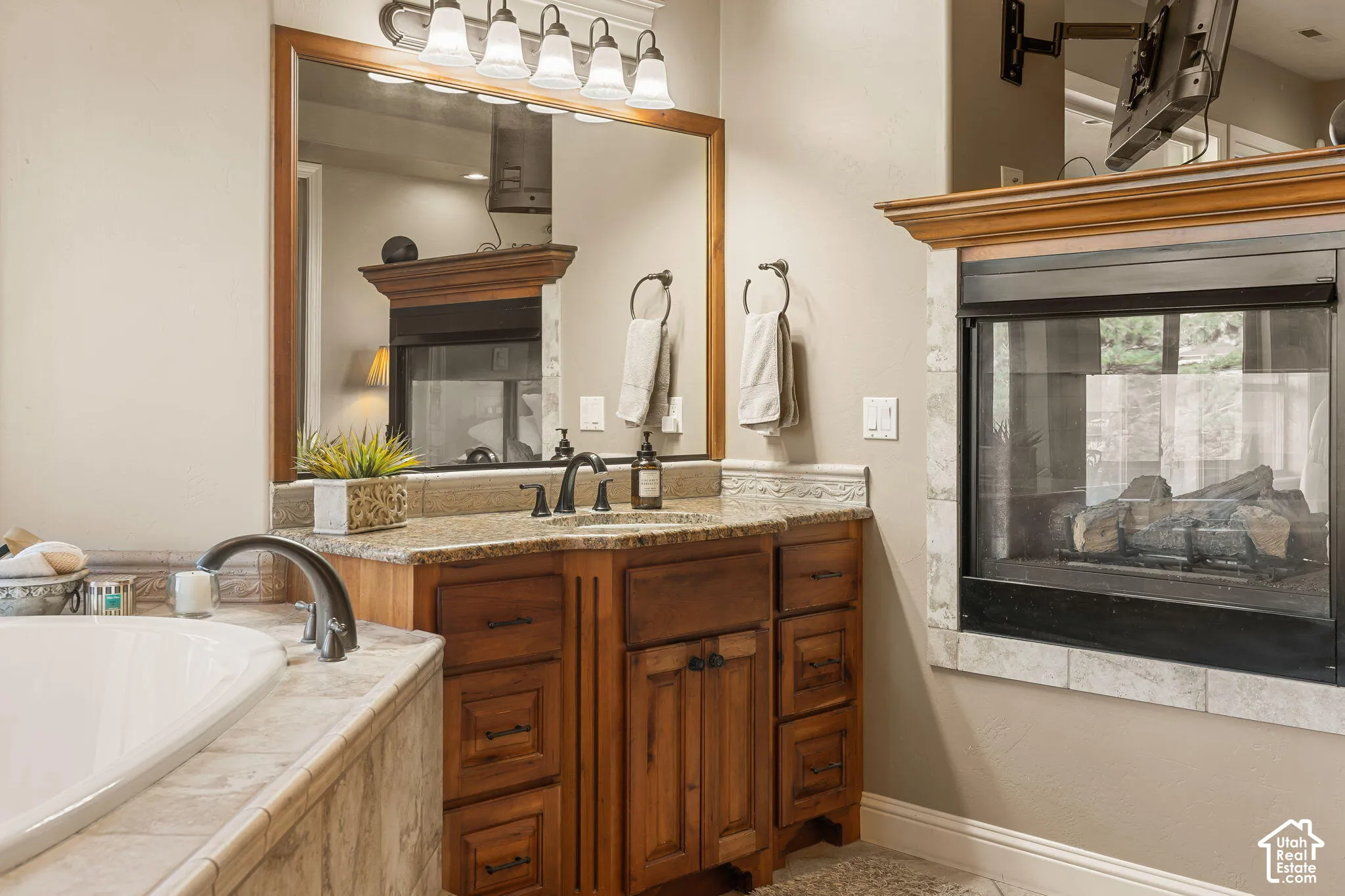 Built-in fireplace with a hearth, wood vanity with a stone countertop, undermount sink, and a wood-framed mirror