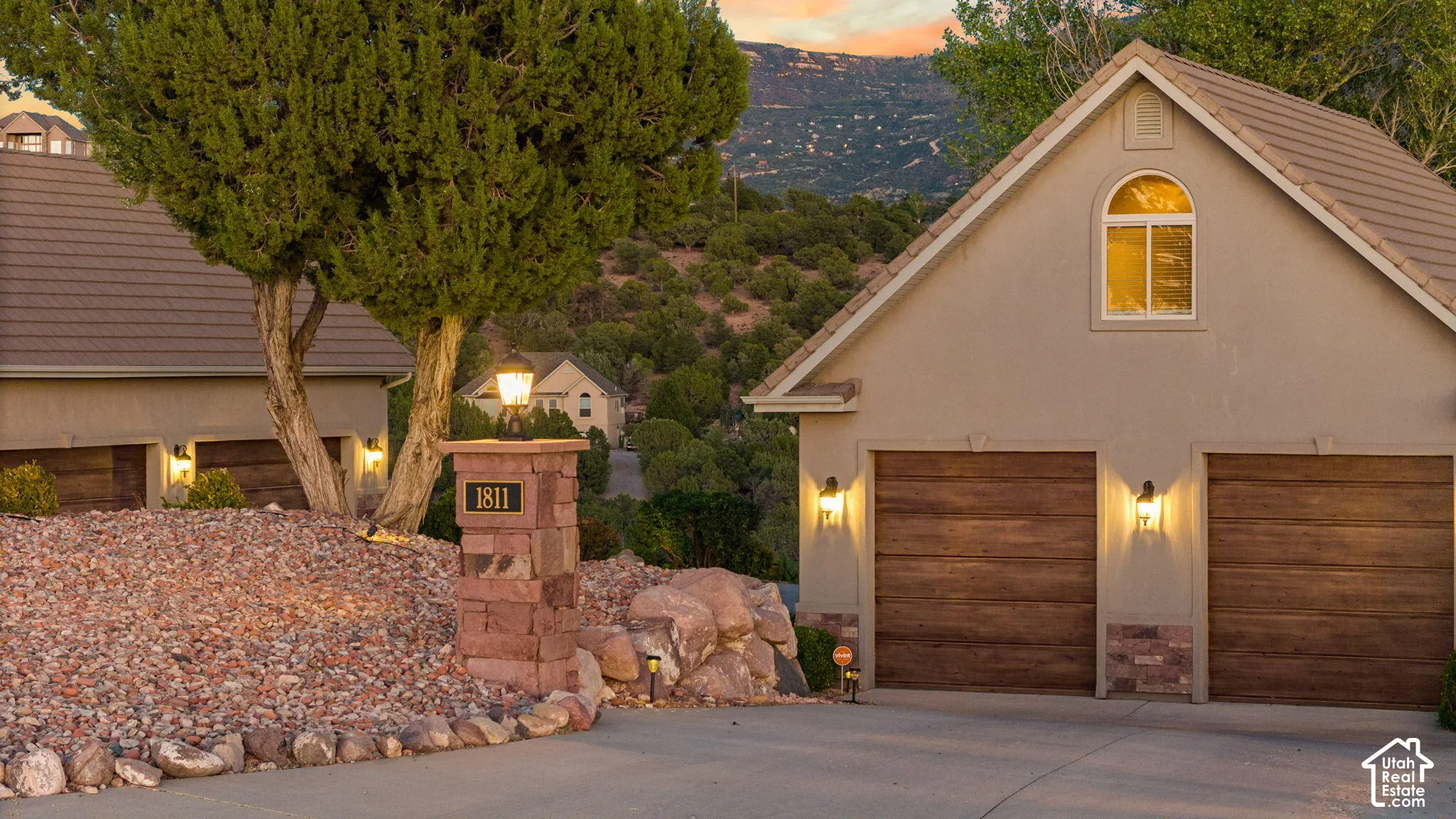 Stucco exterior with a tiled roof, featuring two wood-finish garage doors and an arched window