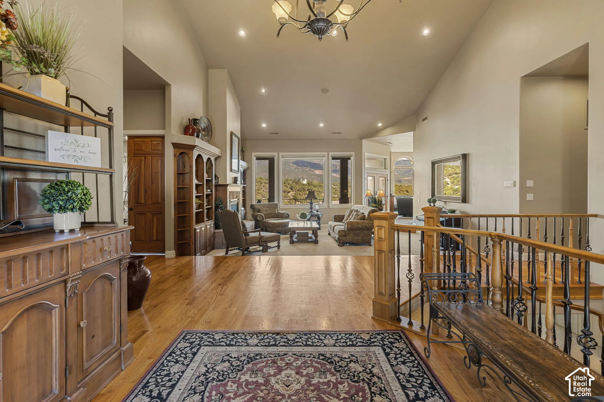 Hardwood flooring, vaulted ceilings, recessed lighting, and a wrought iron and wood staircase railing