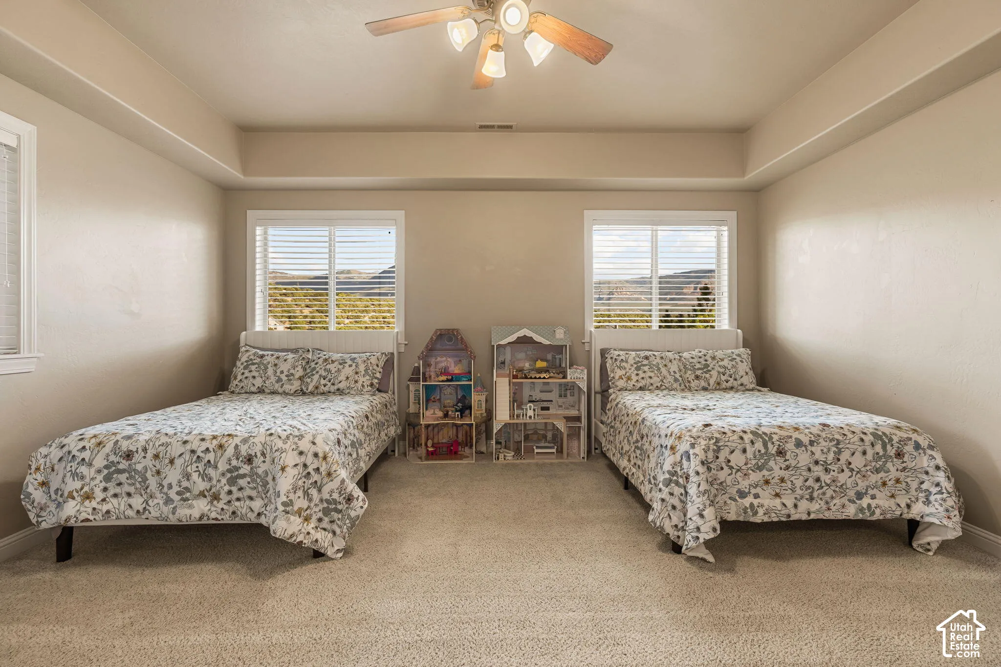 Recessed ceiling with an overhead light fixture and ceiling fan, two windows with horizontal blinds, and wall-to-wall carpeting