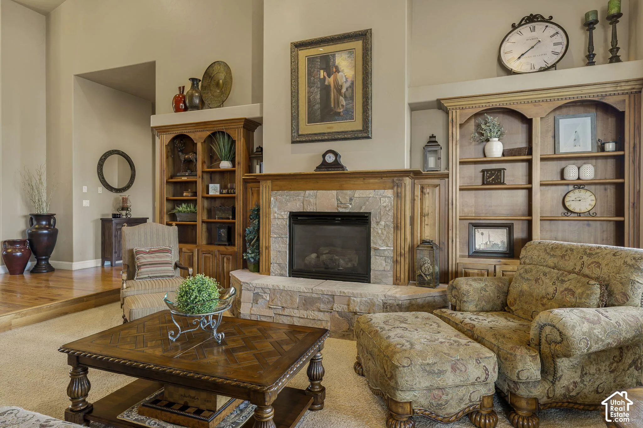 Stone fireplace with a wood mantle, integrated built-in shelving, vaulted ceilings, and wood-finish flooring