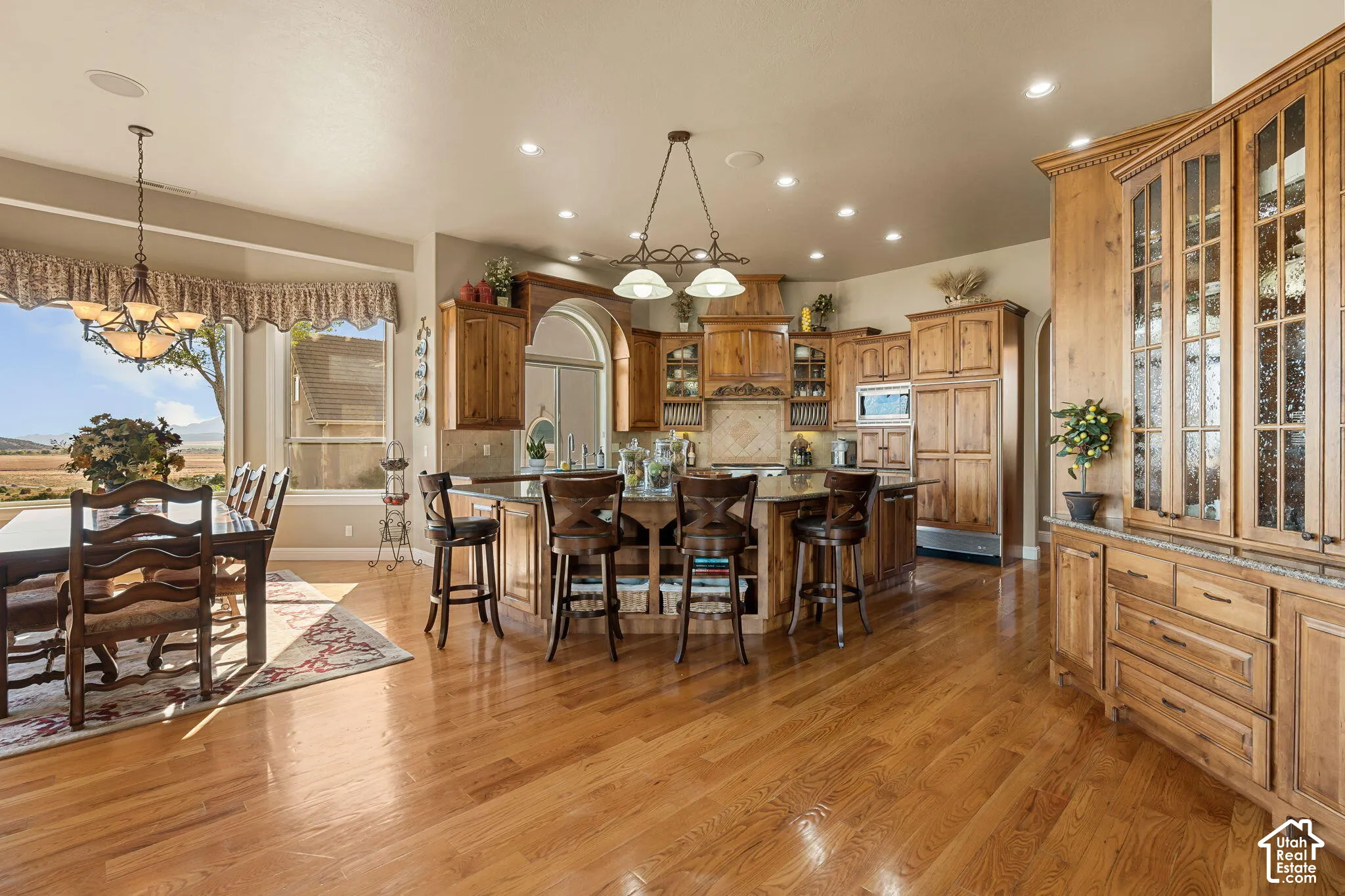 Hardwood flooring throughout, custom wood cabinetry, recessed lighting, built-in display hutch, and a kitchen island with seating