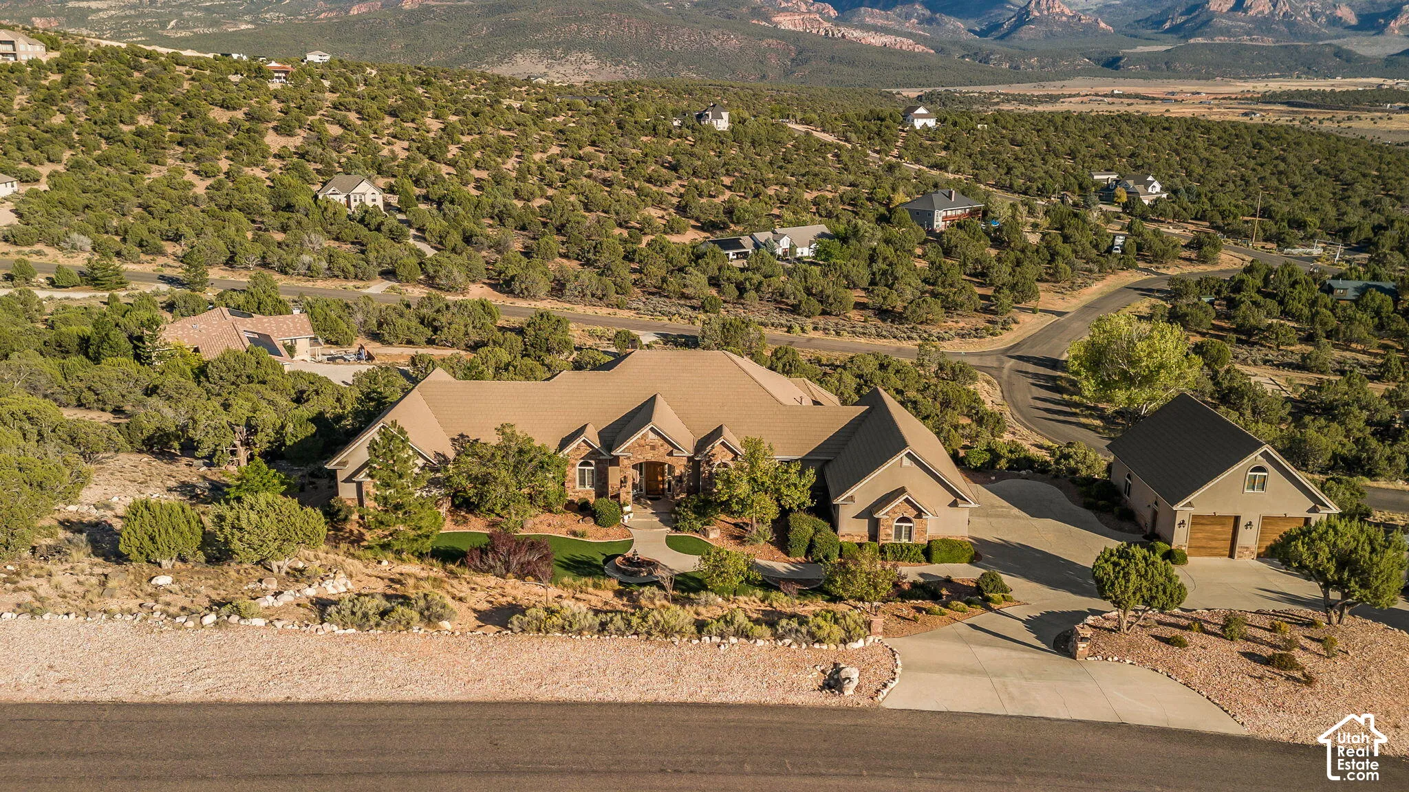Expansive property featuring a multi-level residence with a stone and stucco exterior, a detached garage structure, and a paved driveway