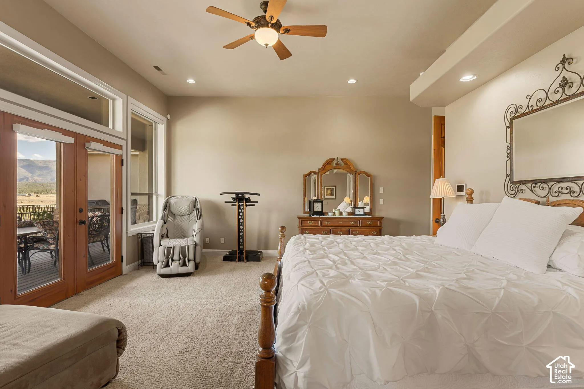 Plush carpeting, wood-finish ceiling fan, recessed lighting, and a glass-paneled double door leading to an outdoor deck