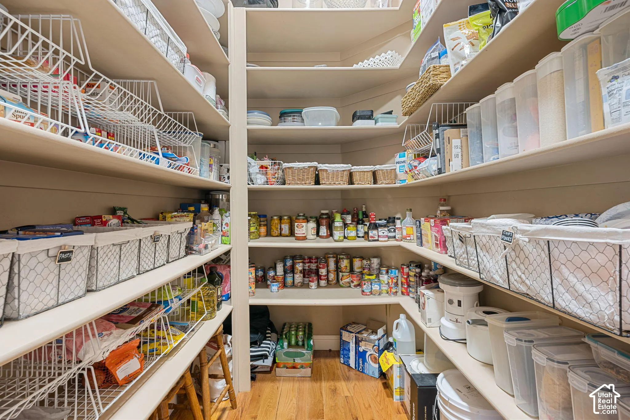 Walk-in pantry featuring extensive built-in shelving, durable wood-finish flooring, and ample storage capacity