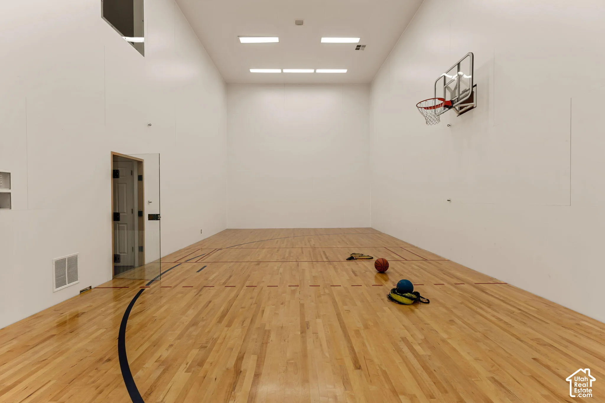 Indoor court with hardwood flooring, basketball hoop, and recessed lighting