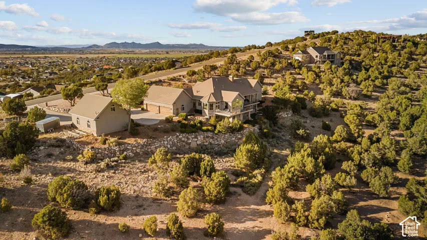 Expansive property set on a natural hillside with mature trees, featuring a multi-level residence with a walk-out lower level, an attached garage, and a detached auxiliary building