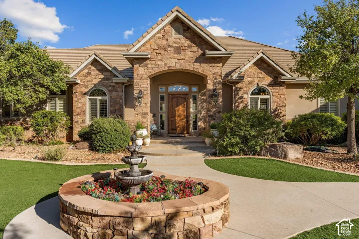 Stone veneer exterior with arched entry, wood-finish front door, arched windows, and tile roof