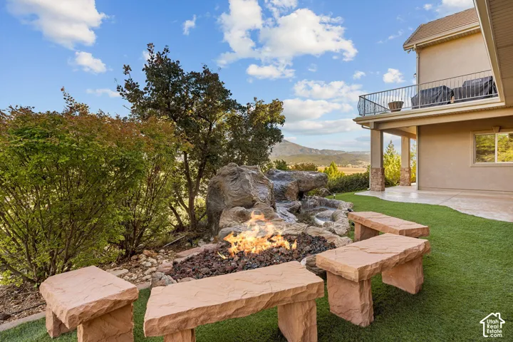 Expansive backyard featuring artificial turf, a rock-detailed water feature, and a built-in fire pit with stone seating