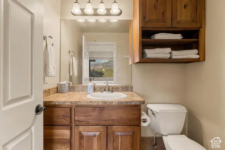 Vanity with a single basin sink, wood cabinetry, and a light-toned countertop