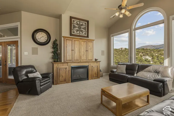 Vaulted ceiling, arched picture window, integrated cabinetry, built-in fireplace, and wood-finish French doors