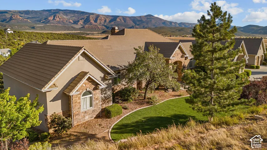Stucco and stone exterior with arched window details, a tiled roof, and a manicured lawn
