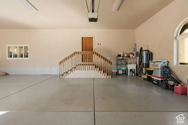 Spacious garage featuring a durable epoxy floor, interior access door, and integrated utility sink