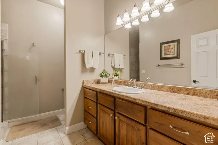 Glass-enclosed shower, wood-finish vanity with ample storage, integrated sink, and a spacious countertop