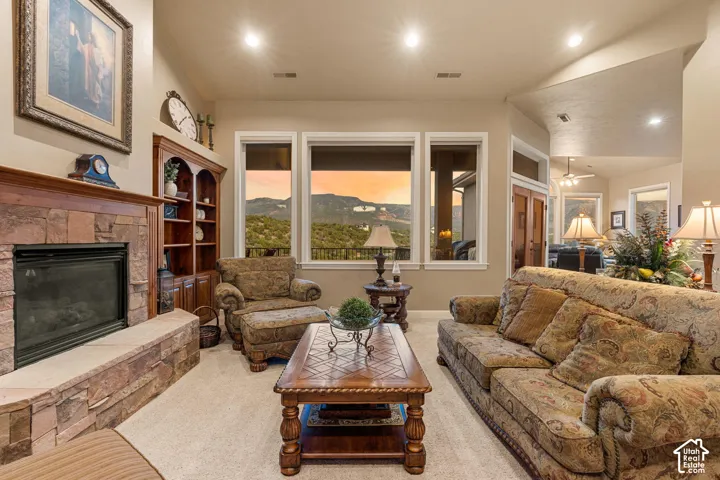 Stone-faced fireplace with hearth, built-in wood cabinetry, recessed lighting, and multiple windows