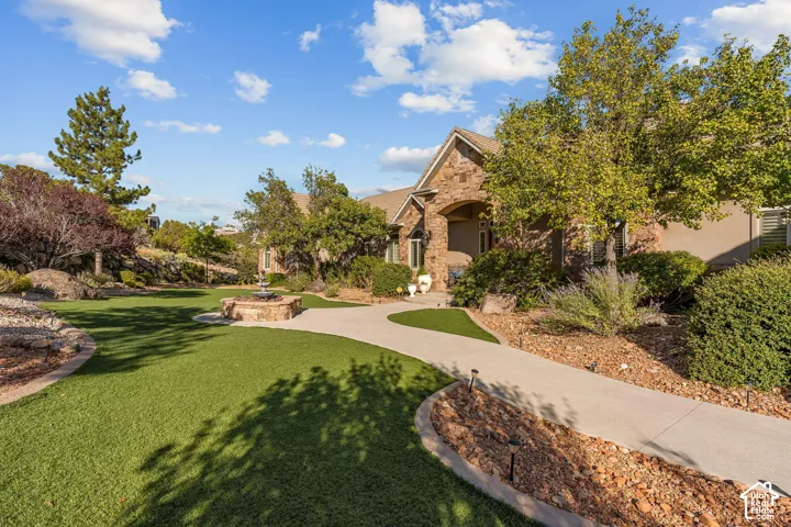 Stone and stucco exterior, arched entry, paved walkways, artificial turf lawn, and a stone-built water feature