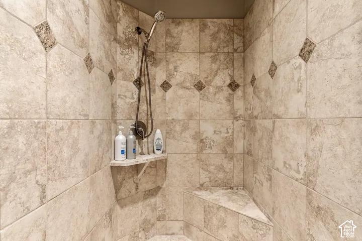 Tiled shower enclosure featuring a corner bench and a built-in shelf