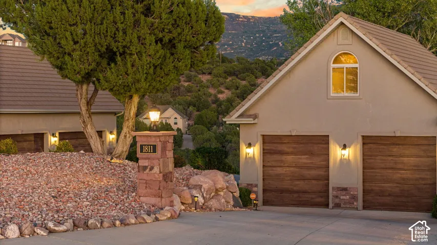 Stucco exterior with a tiled roof, featuring two wood-finish garage doors and an arched window