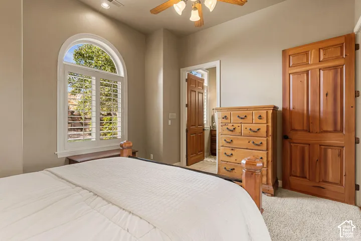 Arched window with plantation shutters, wood-paneled doors, textured carpeting, and a ceiling fan with integrated lighting