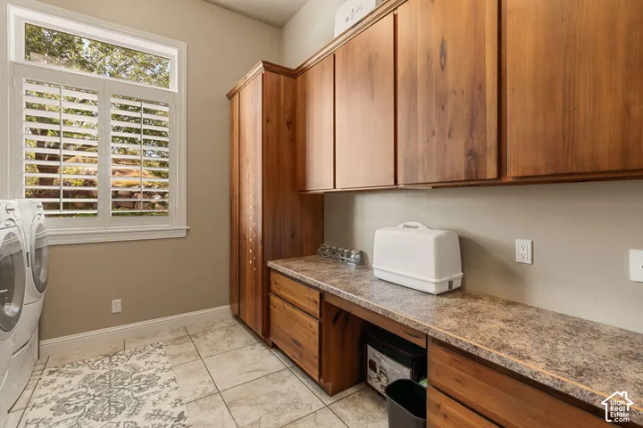 Utility room featuring wood-finish cabinetry, tile flooring, and a window with plantation shutters