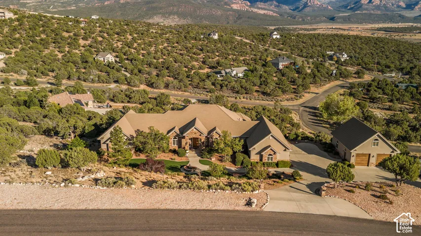 Expansive property featuring a multi-level residence with a stone and stucco exterior, a detached garage structure, and a paved driveway