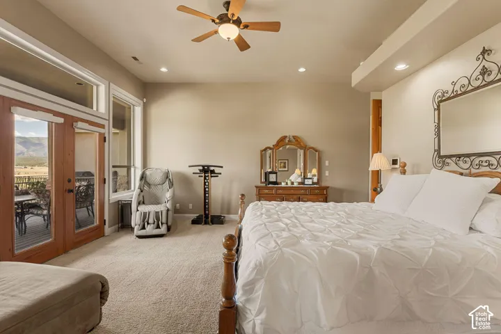 Plush carpeting, wood-finish ceiling fan, recessed lighting, and a glass-paneled double door leading to an outdoor deck