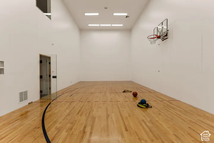 Indoor court with hardwood flooring, basketball hoop, and recessed lighting