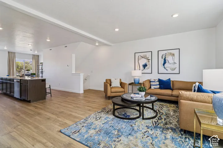 Recessed lighting illuminates the open-concept living space with wood-finish flooring
